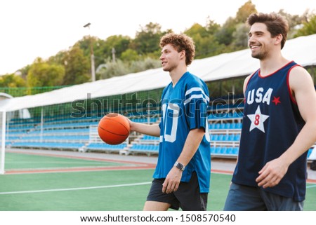 Two smiling confident basketball players walking at the playground, ready to play basketball