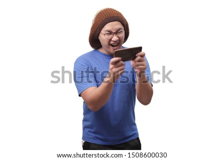 Photo image portrait of a cute handsome young Asian man with funny face playing games on tablet smart phone