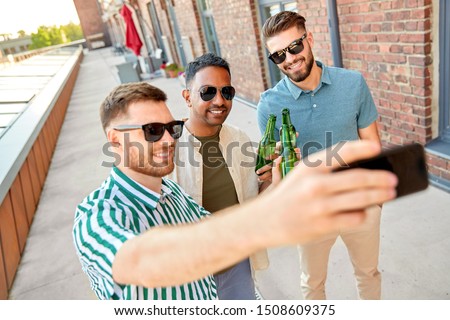 leisure, technology and people concept - happy male friends taking selfie by smartphone and drinking beer at rooftop party in summer city,