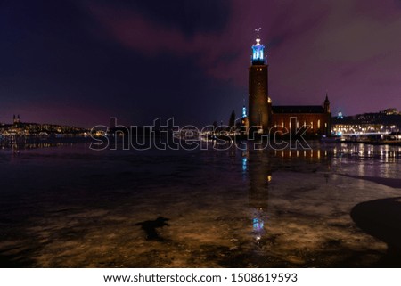 Picture of the ancient town of Stockholm city on a typical Scandinavian cold winter night. Reflection of the ancient city hall building on the iced water