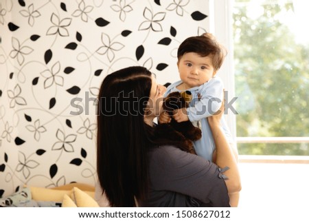 Pregnant Mother holding playing with her baby son talking with him - Asian mixed ethnicity child Boy wearing blue body shirt with smiling bear cartoon