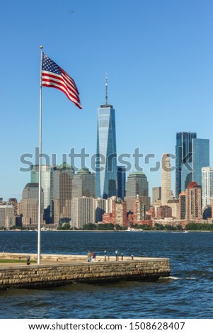 Skyline of Manhattan with the American flag on the left and One World Trade Center in the background, Ellis Island, New York, United States of America.