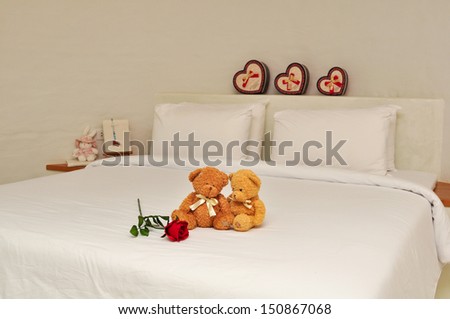 rose and two teddy bears on bed