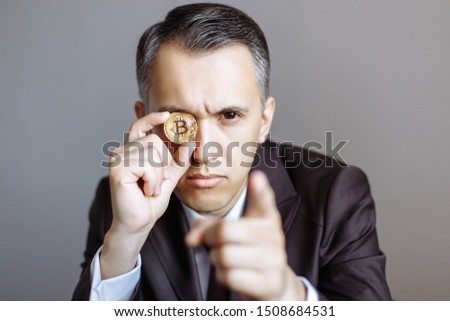 Successful young businessman in suit with bitcoin on gray background.