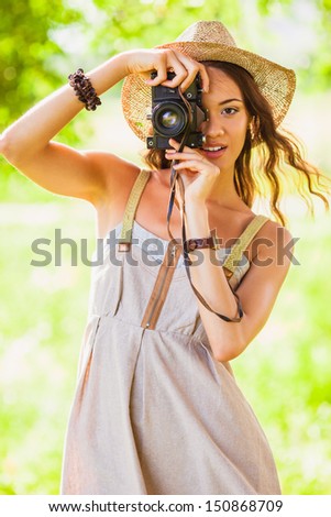 happy young girl shooting with vintage camera in the park