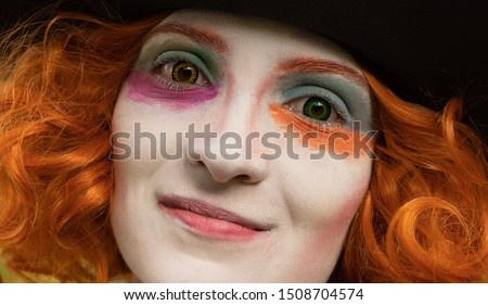 Portrait of a beautiful young woman with red hair, 
different colored contact lenses and colorful make-up