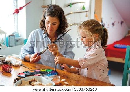 Mother and daughter painting Christmass ornaments	
