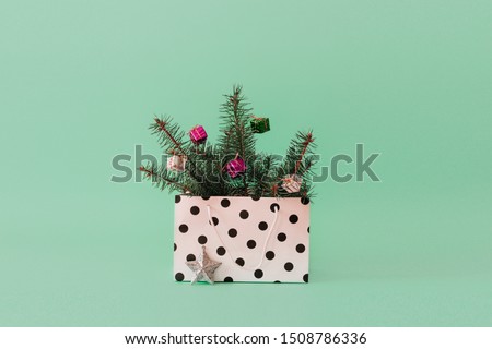 Christmas composition with Conifer Evergreen tree branches and bauble ball in gift bag. Christmas and 2020 new year minimal concept on pastel background, copy space