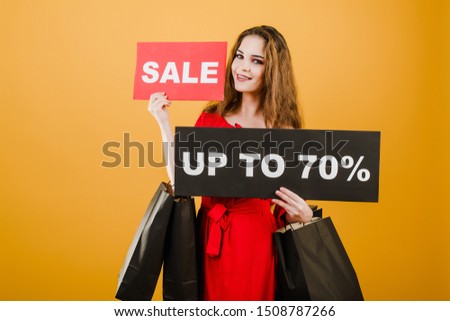 smiling woman has sale up to 70% sign with paper shopping bags isolated over yellow