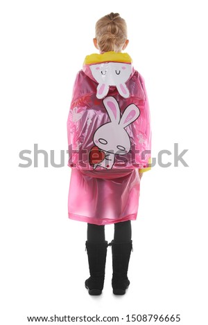 Full length back shot of a little blonde girl dressed in a cherry-coloured nacre raincoat, black jeans and black high shammy boots. 