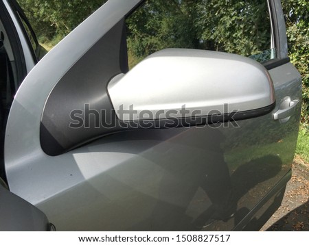 Open passenger door of a silver colour car showing back of wing mirror cover with lower cover in black with copy space for text