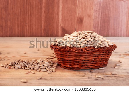 filled with sunflower seeds wicker basket on a wooden table background is also wooden dark shade. the basket is handmade and treated seeds
