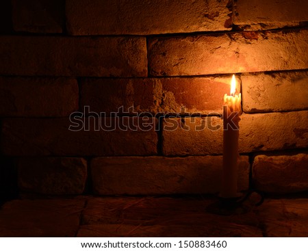 Single burning candle on the brick background in night 3