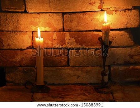 Two burning candles on the brick wall background in night