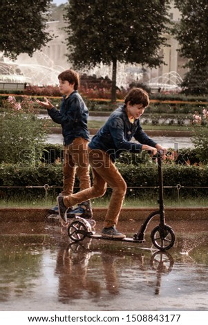 Twin brothers ride a scooter and roller skates in the park. Healthy lifestyle. Sport family