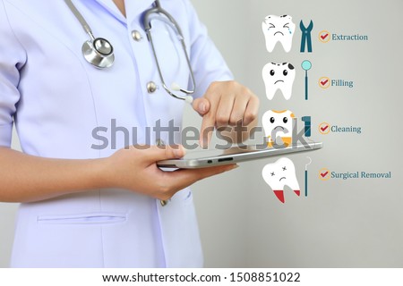 Dentist's using tablet smart device with icon set of teeth treatment and problem of tooth loss on white background, Dentistry and Tooth hygiene concept