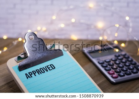 Approved finance business concept with words on blue lined paper clipboard and calculator