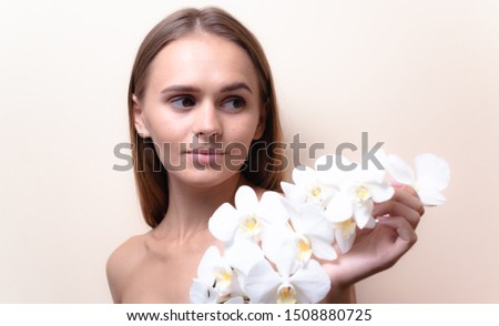 Closeup portrait of a beautiful model with white orchid flowers.