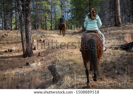 Woman riding horse with man riding horse in the background