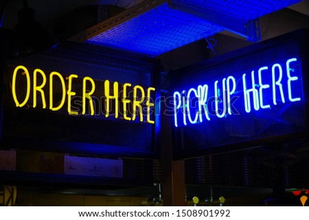 Order here and pick up here neon signs in a bar.                                 
