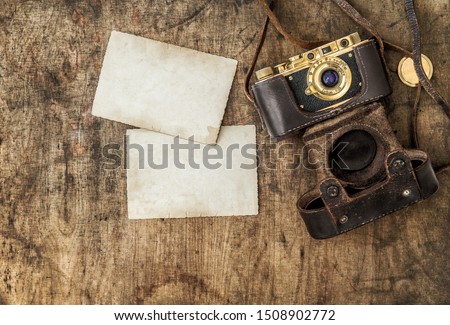 Vintage film camera and old photos on wooden background. Nostalgic still life