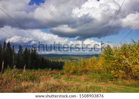 Autumn landscape multi-colored foliage of forest trees in the mountains against the sky and clouds.