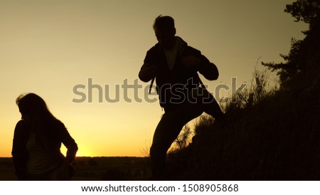 male traveler and female traveler descend from top of the hill. teamwork of business people. tourists descend from the mountain in the sunset, one after another. Happy family on vacation.