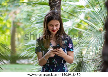 Happy woman chatting on smartphone in park