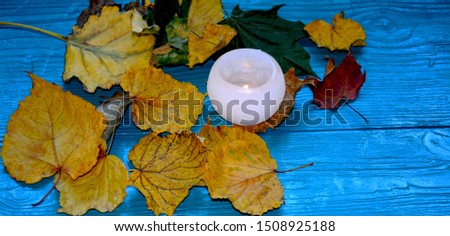 Autumn yellow leaves, burning candles on a turquoise background ... direct sunlight ...