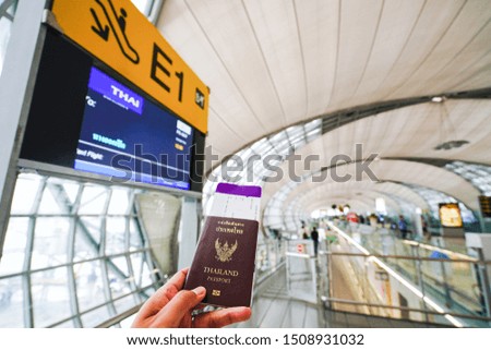 The left hand holds the passport with boarding pass to walk to the boarding gate.Stock photo.