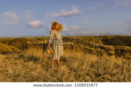 amazing girl in a hat at sunset in the steppe on the sea, girl with developing hair