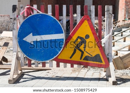 Barrier before construction. Old signs warning of construction work and detour.