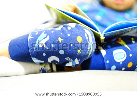 Boy in pajamas reading cartoon book on sofa