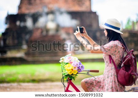 woman tourist enjoy riding local bicycle to see the historic park of Thailand, taking photo to the wonderful place of sightseeing