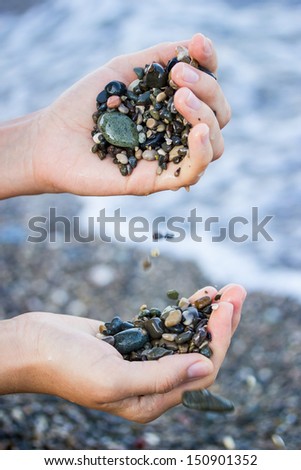 A girl plays with sea stones on the seashore