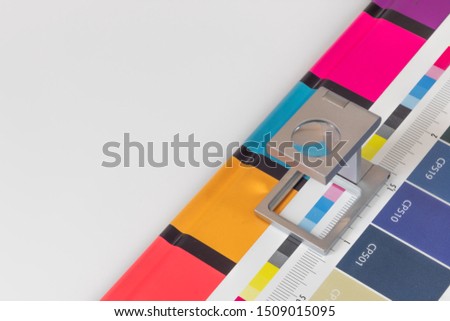 Silver magnifying glass standing on  the test print, colored background. Print loupe on offset printed sheet with basic colors control bars. Royalty-Free Stock Photo #1509015095