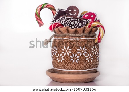 New Year and Christmas holiday concept. Holiday sweets and candies, gingerbread in clay pot on white background. Homemade holiday bakery.