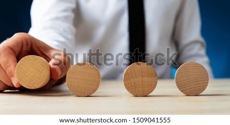 Businessman placing four blank wooden circles in a row on a desk.