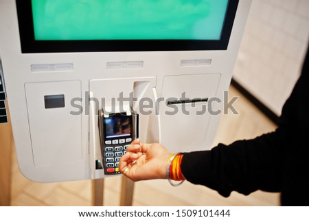 Hands of man customer at store place orders and pay by credit card through self pay floor kiosk for fast food, payment terminal. 