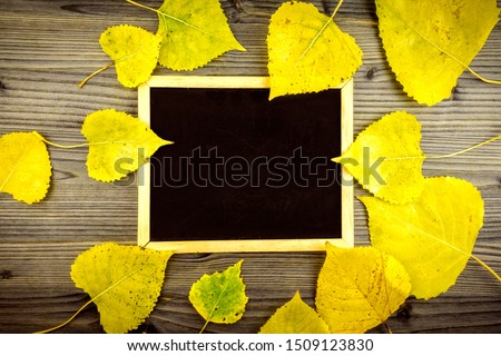 Colorful yellow autumn leaves on wooden table and blackboard with copy space