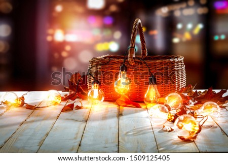 Wooden table background with basket and light bulbs. Blurred colorful lights view.