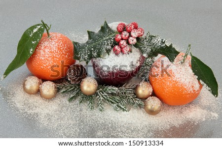 Christmas decoration with apple and mandarin orange fruit over silver grey background.