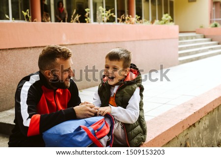 Smiling father and son in front of the school