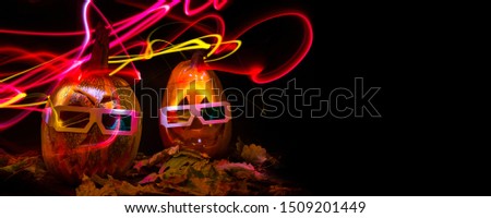 luminous pumpkins in the dark for the autumn Halloween holiday. 3D movie for Halloween. Pumpkin Head Jack in 3D glasses for the movie. Bright neon pink and blue light in the darkness of Freezelight
