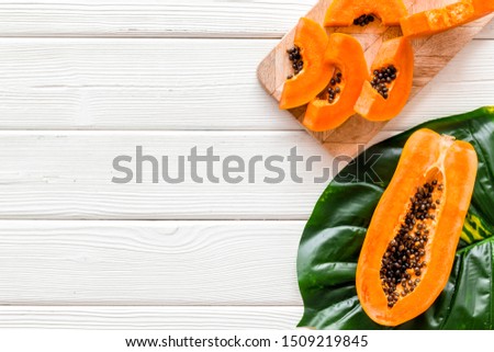 Papaya slices on white wooden background top view space for text