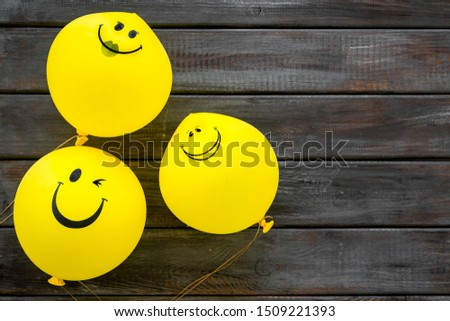 Happiness emotion. Yellow balloon with smile on dark wooden background top view copy space