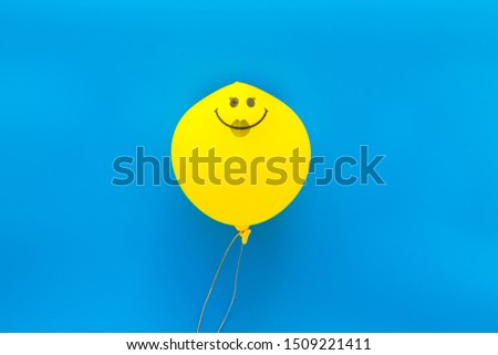 Happiness emotion. Yellow balloon with smile on blue background top view copy space