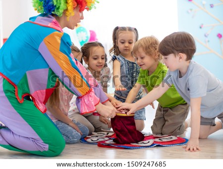 Group of happy smiling preschool kids watching at clown show indoor. Party for children.