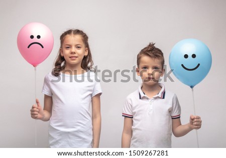 Smiling girl and boy closeup isolated on grey background . Image.  holding balls in their hands
