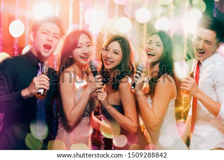 young group holding microphone and singing at karaoke